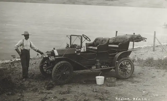 Man with an early automobile on the lakeshore